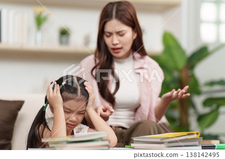Mother assisting daughter with schoolwork at home 138142495