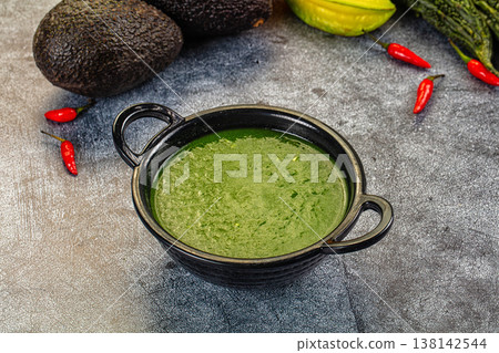 Green Spinach vegetable soup in a bowl with fresh avocado and chili peppers 138142544