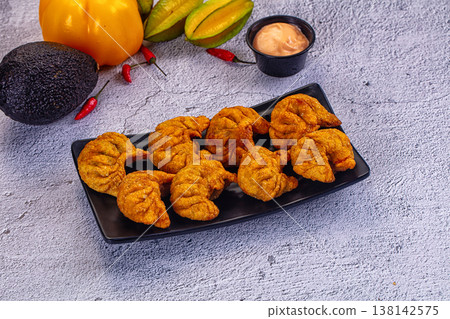 Fried dumplings Momo on a plate with creamy sauce, avocado, and chili peppers Fried dumplings Momo on a plate with creamy sauce, avocado, and chili peppers 138142575