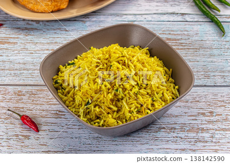 Bowl of yellow basmati rice pilaf with herbs, served with appetizers on a rustic wooden table. Bowl of yellow basmati rice pilaf with herbs, served with appetizers on a rustic wooden table. 138142590