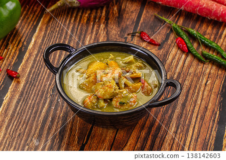 Thai green curry with shrimp and broccoli in a bowl, surrounded by fresh ingredients on a wooden table Thai green curry with shrimp and broccoli in a bowl, surrounded by fresh ingredients on a wooden table 138142603