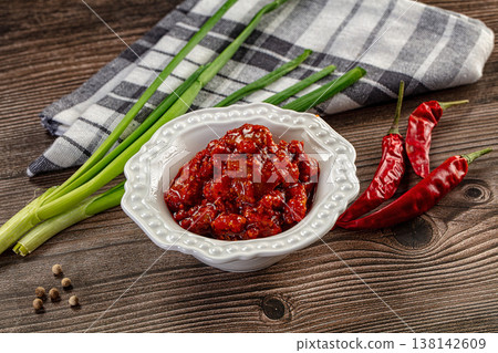 Spicy red chili pickle in a white bowl on a rustic wooden table with fresh ingredients Spicy red chili pickle in a white bowl on a rustic wooden table with fresh ingredients 138142609