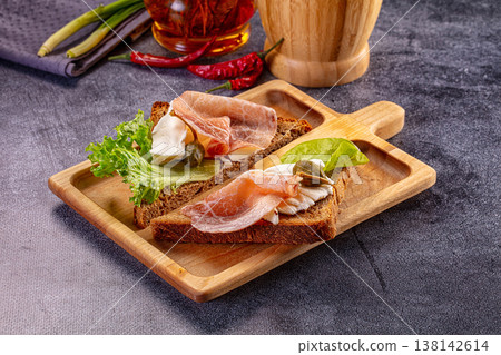Gourmet open-faced sandwiches with prosciutto and cheese on a wooden board 138142614