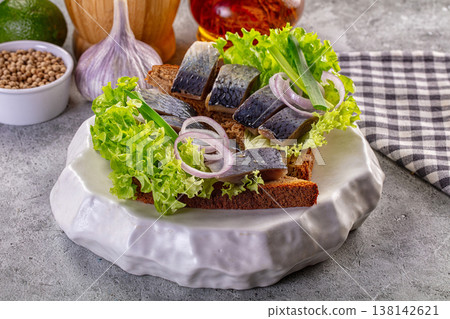 Traditional pickled herring sandwich on rye bread with lettuce and red onion 138142621
