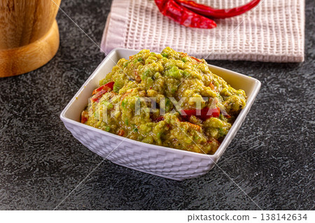 Freshly made chunky guacamole in a white bowl, served as a traditional Mexican appetizer on a dark tabletop. Freshly made chunky guacamole in a white bowl, served as a traditional Mexican appetizer on a dark tabletop. 138142634