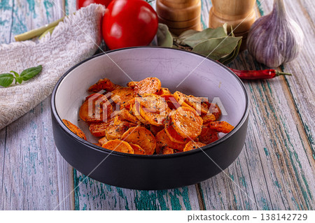 Bowl of roasted carrot slices with herbs on a rustic wooden table with fresh vegetables 138142729