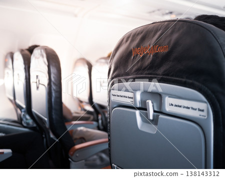 seat rows in an airplane cabin, Interior of commercial airplane with unrecognizable passengers on their seats during flight shot from the rear of airplane. 138143312