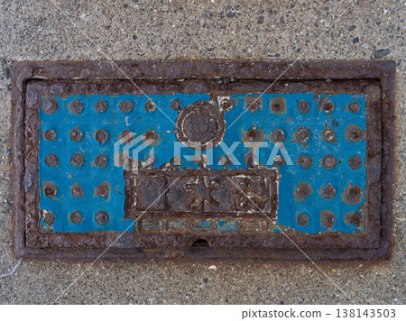 Rusty blue metal inspection hatch cover on a grunge textured concrete background. 138143503