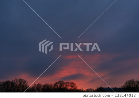 Dramatic dark evening sky with bright red sunset above winter trees Dramatic dark evening sky with bright red sunset above winter trees 138144018