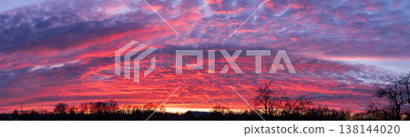 Epic panoramic fiery sunset sky with textured clouds and tree silhouettes Epic panoramic fiery sunset sky with textured clouds and tree silhouettes 138144020