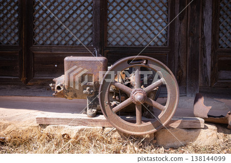 Rusty vintage industrial machine with wheel in front of traditional Korean house Rusty vintage industrial machine with wheel in front of traditional Korean house 138144099