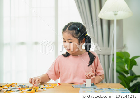 Young girl engaged in creative building with colorful construction blocks in a bright indoor space, focusing on playful learning and development 138144283
