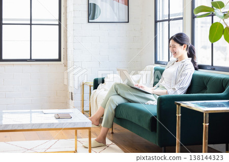 Young woman using a computer in the living room Young woman using a computer in the living room 138144323