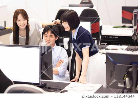 男男女女一邊看著電腦一邊交談。 138144344