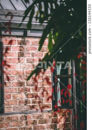 Rustic Red Brick Wall with Black Window Frame and Red Leaf Foreground Rustic Red Brick Wall with Black Window Frame and Red Leaf Foreground 138144350