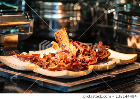 Heap of Crispy Fried Bacon Strips on Toasted Bread in Hotel Kitchen Heap of Crispy Fried Bacon Strips on Toasted Bread in Hotel Kitchen 138144494