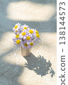 Top View of Small Daisy Vase with Beautiful Sunlight and Shadow on Table 138144573