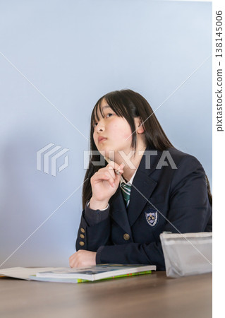 A female student in a uniform thinking deeply A female student in a uniform thinking deeply 138145006