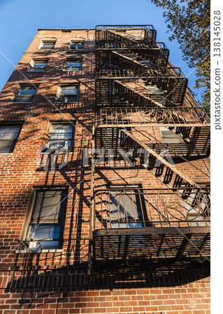 Low angle view of New York brick apartment building with metal fire escape Low angle view of New York brick apartment building with metal fire escape 138145028