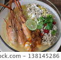 Tom Yum Kung Noodle Bowl with River Prawns, Poached Egg, Minced Pork, Lime, Chili, Herbs, and Aromatic Broth Served in a White Bowl 138145286