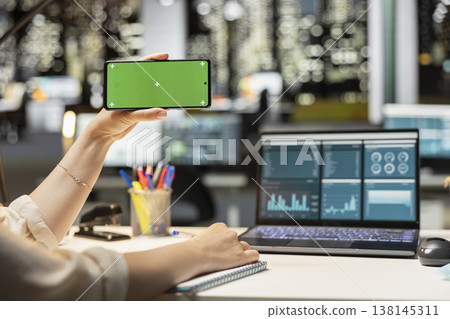 Green screen mockup with woman looking at mobile phone during work session at night, finishing business management tasks after hours in corporate office. Using isolated chroma key. Green screen mockup with woman looking at mobile phone during work session at night, finishing business management tasks after hours in corporate office. Using isolated chroma key. 138145311