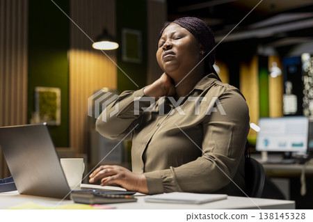 Female assistant in discomfort due to neck stiffness and backache, doing self massage to relieve the pain and strain. Businesswoman struggling with incorrect posture at the office. Female assistant in discomfort due to neck stiffness and backache, doing self massage to relieve the pain and strain. Businesswoman struggling with incorrect posture at the office. 138145328