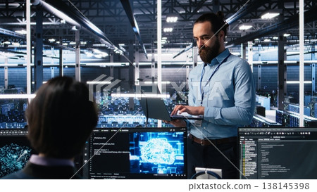 Manager supervising work of server room engineer using AI to review infrastructure diagnostics on devices. Tech company supervisor overseeing IT expert in data center analyzing data using AI, camera A 138145398