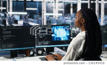 Female programmer in data center reviews AI diagnostics, analyzing neural network performance. Server hub IT expert optimizes artificial intelligence systems configuration, camera A Female programmer in data center reviews AI diagnostics, analyzing neural network performance. Server hub IT expert optimizes artificial intelligence systems configuration, camera A 138145418