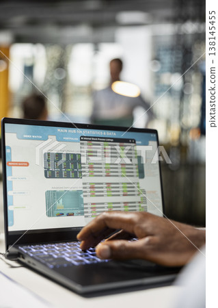 Close up of financial advisor analyzing company statistics for successful investment plans on laptop at office desk. Black male individual reviews sales projections on device in modern workplace. Close up of financial advisor analyzing company statistics for successful investment plans on laptop at office desk. Black male individual reviews sales projections on device in modern workplace. 138145455