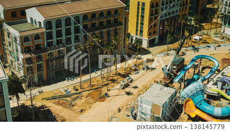 Aerial view of resort construction site with heavy machinery and partially built structures 138145779