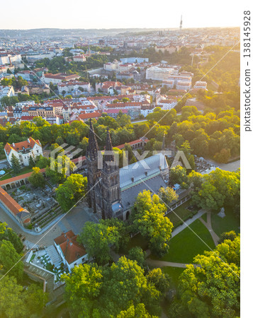 The magnificent Vysehrad Basilica of St. Peter and St. Paul rises among lush greenery as the sun rises over Prague, illuminating the historic cityscape in the early morning light. The magnificent Vysehrad Basilica of St. Peter and St. Paul rises among lush greenery as the sun rises over Prague, illuminating the historic cityscape in the early morning light. 138145928