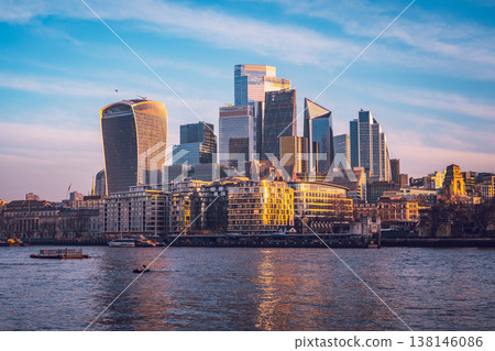 The City of London awakens with a stunning skyline reflecting on the Thames River. Early morning light highlights the modern buildings and the tranquility of the water. 138146086