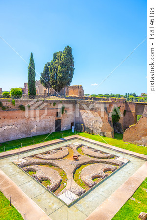 Visitors see the Fountain of the Pelte in the Roman Forum. The historic site features ancient ruins, green grass, and trees. It attracts tourists and history lovers daily. 138146183