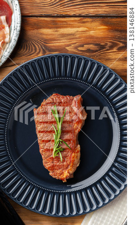 Grilled steak served on a blue plate with herbs at a restaurant table Grilled steak served on a blue plate with herbs at a restaurant table 138146884