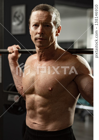 Man lifts barbell at gym in the afternoon while focusing on strength training and fitness goals 138146910