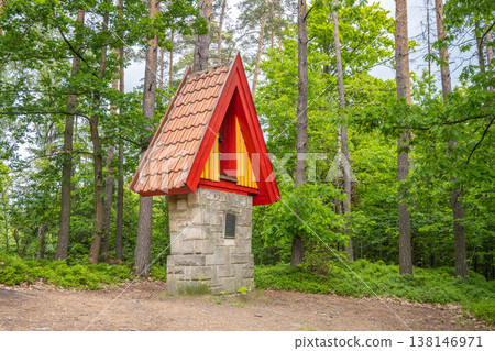 A small belfry stands in a forest at Prachovske sandstone rocks. It features a red roof and is surrounded by green trees during a sunny day. Visitors can enjoy the natural setting. A small belfry stands in a forest at Prachovske sandstone rocks. It features a red roof and is surrounded by green trees during a sunny day. Visitors can enjoy the natural setting. 138146971