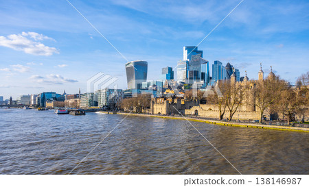 View of London skyline featuring the iconic Tower and modern skyscrapers along the River Thames. The scene captures the beauty of the city against a clear blue sky. View of London skyline featuring the iconic Tower and modern skyscrapers along the River Thames. The scene captures the beauty of the city against a clear blue sky. 138146987