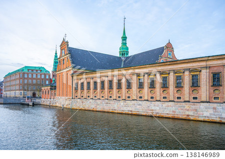 Holmen Church is located in central Copenhagen, Denmark. The building features green spires and brick walls. It sits next to the water under a cloudy sky. Holmen Church is located in central Copenhagen, Denmark. The building features green spires and brick walls. It sits next to the water under a cloudy sky. 138146989