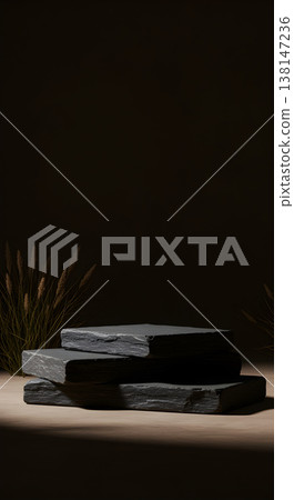 Three natural slate stone pedestals in a minimalist dark setting with dry grass, ideal for product display. 138147236