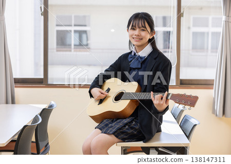 一個女孩微笑著彈著吉他。 一個女孩微笑著彈著吉他。 138147311
