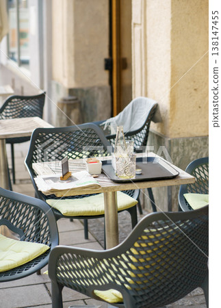 Cozy outdoor cafe table with drinks and newspaper, European street scene, relaxed atmosphere, lifestyle, travel and leisure concept Cozy outdoor cafe table with drinks and newspaper, European street scene, relaxed atmosphere, lifestyle, travel and leisure concept 138147455