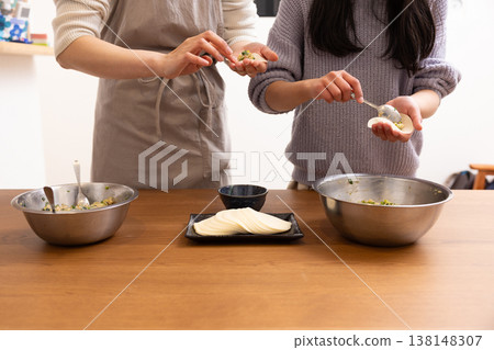 一位婦女和一位女孩正在包餃子皮 一位婦女和一位女孩正在包餃子皮 138148307