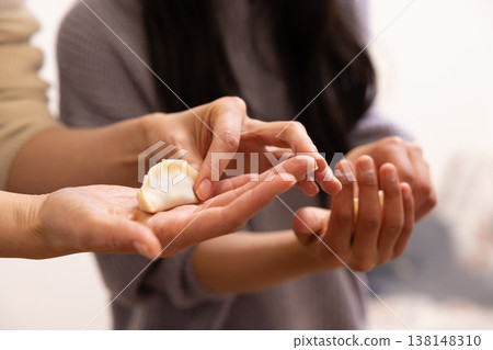 The hands of a woman and a girl wrapping dumpling wrappers 138148310