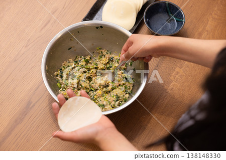 特寫鏡頭：雙手將餃子餡包進餃子皮裡。 138148330