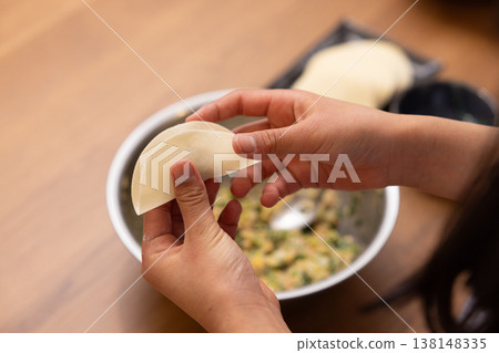 特寫鏡頭：雙手將餃子餡包進餃子皮裡。 138148335