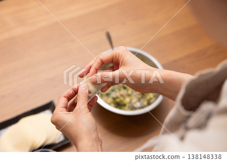 特寫鏡頭：雙手將餃子餡包進餃子皮裡。 138148338