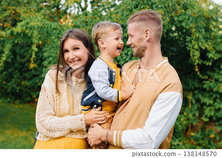 Smiling Parents Holding Child Outdoors Together Smiling Parents Holding Child Outdoors Together 138148570