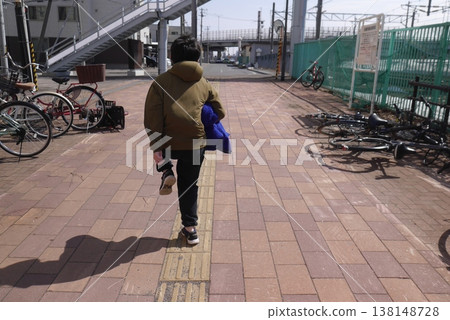 一個孩子走在車站前的街道上(從後面拍攝)。 一個孩子走在車站前的街道上(從後面拍攝)。 138148728