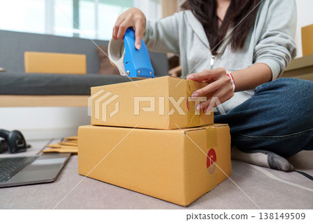 Woman packing and sealing cardboard boxes for shipping Woman packing and sealing cardboard boxes for shipping 138149509