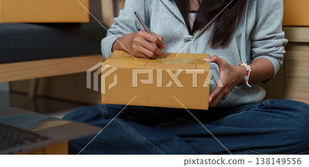 Woman labeling a package for delivery Woman labeling a package for delivery 138149556